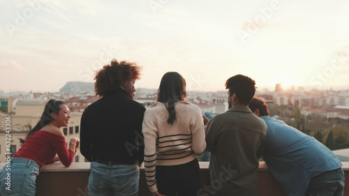 Guys and girls at the party, looking at the beautiful views and talking standing on the terrace, friendly party holiday at sunset © Andrii Nekrasov