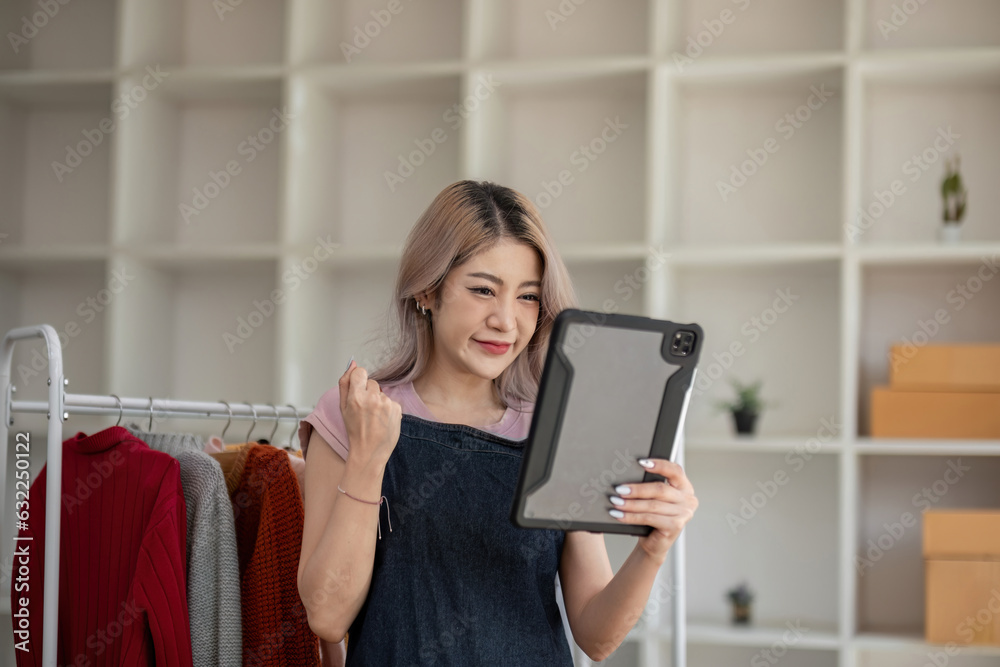 businesswoman owner an online trading business is using tablet to check the stock of the clothes on the rail rack at small office at home. work from home, online delivery, SME. businesswoman owner an online trading business is using tablet to check the stock of the clothes on the rail rack at small office at home. work from home, online delivery, SME.