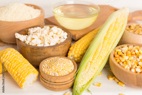 Maize products with fresh corn cobs on wooden table