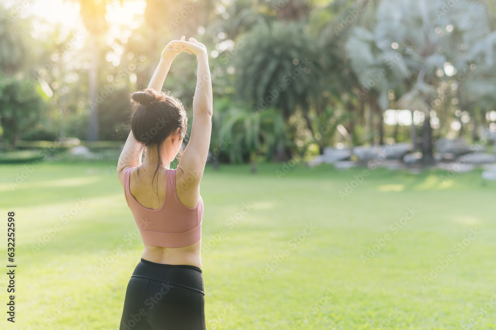 Φωτογραφία Back portrait of a 30s Asian woman, wearing pink sportswear, preparing her body and breathing fresh air before a sunset run in a public park