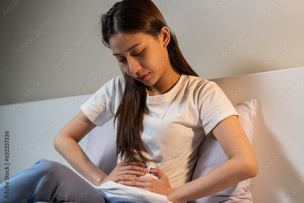 Flatulence ulcer, asian young woman hand on belly, stomach ache from food poisoning, abdominal pain and digestive problem, gastritis or diarrhoea sitting in bed room in the night. Abdomen inflammation Flatulence ulcer, asian young woman hand on belly, stomach ache from food poisoning, abdominal pain and digestive problem, gastritis or diarrhoea sitting in bed room in the night. Abdomen inflammation