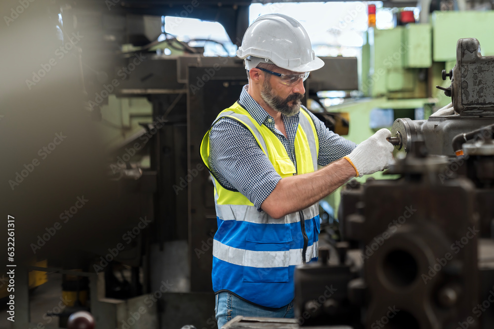 Staff or technicians are checking the operation of the old machine via the remote. Man worker in safety helmet working on steel machine. Staff or technicians are checking the operation of the old machine via the remote. Man worker in safety helmet working on steel machine.