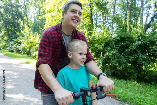 Father teaches his son how to ride an electric scooter. Riding an e-scooter without protective gear. Increased risk of injury when using battery powered vehicles. Concept of problems in safety driving