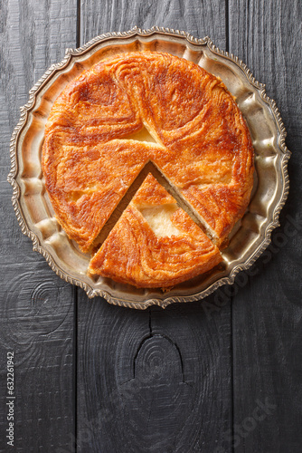 Kouign amann is a round multi-layered cake containing with laminated dough soaked in butter and sugar closeup on the plate on the table. Vertical top view from above photo