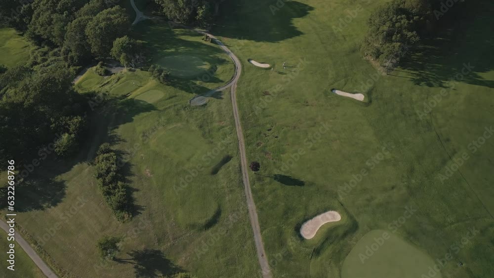 Aerial View of a Green Golf Course at Sunset. Set Shot, the Drone Flew Over the Golf Club. Cinematic Overhead View on Active Men Playing the Golf Game on a Sunny Summer Day Aerial View of a Green Golf Course at Sunset. Set Shot, the Drone Flew Over the Golf Club. Cinematic Overhead View on Active Men Playing the Golf Game on a Sunny Summer Day