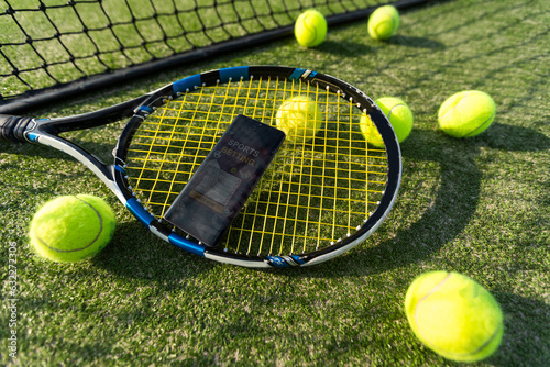 High angle view of mobile phone with tennis equipment on black background