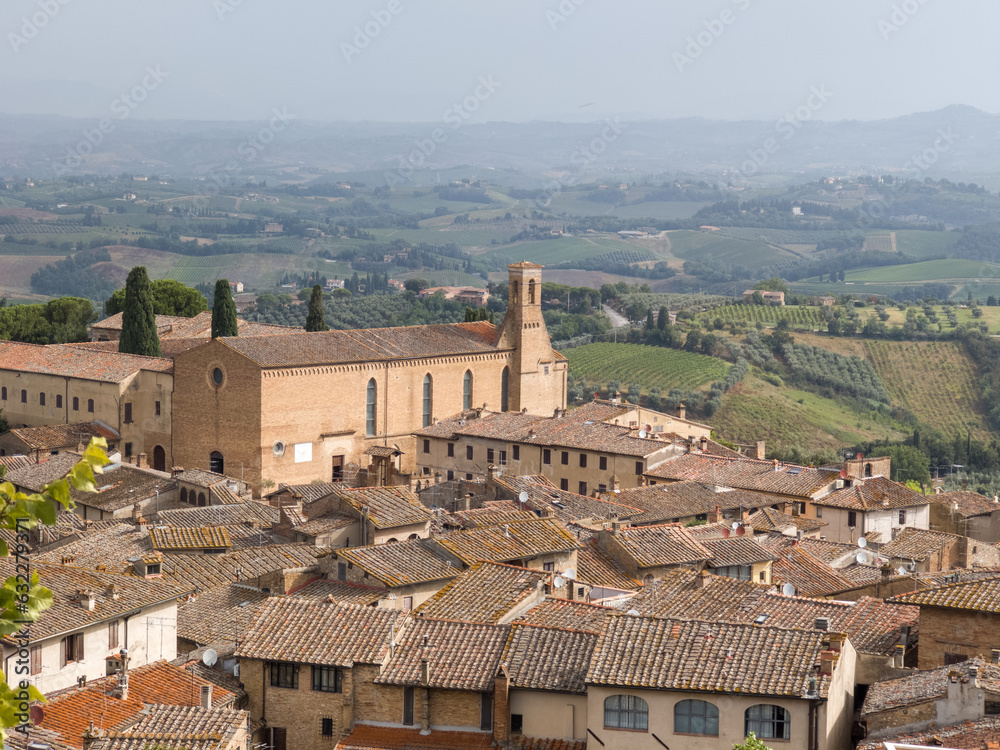 Exterior View of the Walls of the Convent of Sant'Agostino and the Bell Tower in San Gimignano with the surrounding Trees, Siena - Italy.