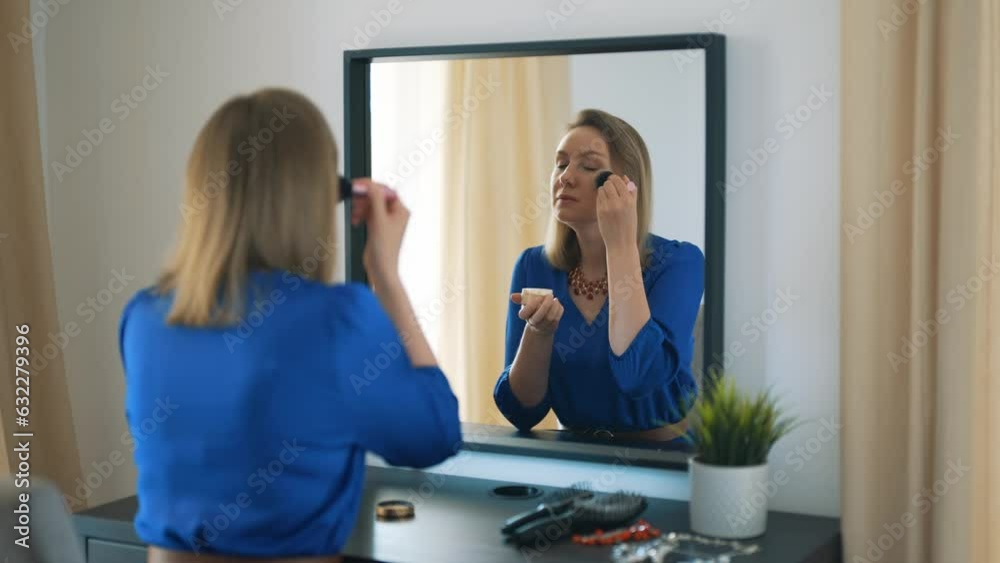Woman doing makeup in front of mirror. Applying powder on face. Woman doing makeup in front of mirror. Applying powder on face.