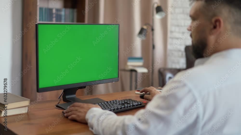 Successful Middle Aged Bearded Businessman Working at His Desk Using Computer with Green Mock-up Screen. Man Working from Cozy Home Office, Studio