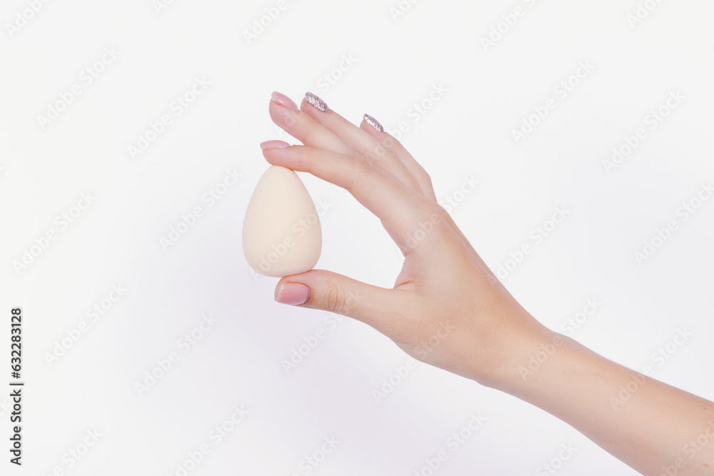 Woman hand holding beauty blender on the white background. Woman hand holding beauty blender on the white background.
