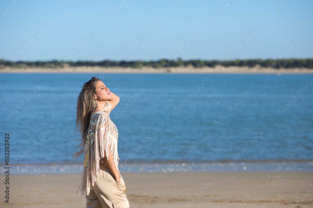 Beautiful young blonde woman walks on the sand of the beach on the south coast of spain in Sanlucar de barrameda, city of wine and gastronomy, in the background river mouth and national park Beautiful young blonde woman walks on the sand of the beach on the south coast of spain in Sanlucar de barrameda, city of wine and gastronomy, in the background river mouth and national park