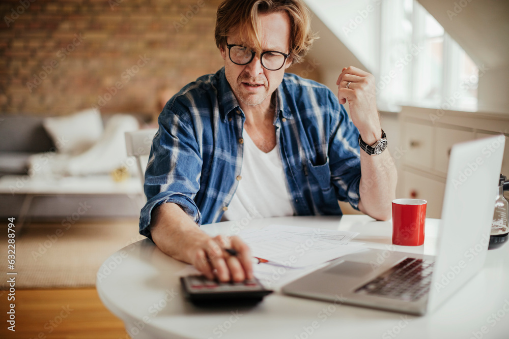 Mature man calculating and going over his bills and home finances Mature man calculating and going over his bills and home finances