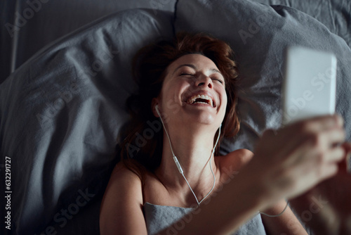 Young woman using a smart phone in the bed in the bedroom in the morning