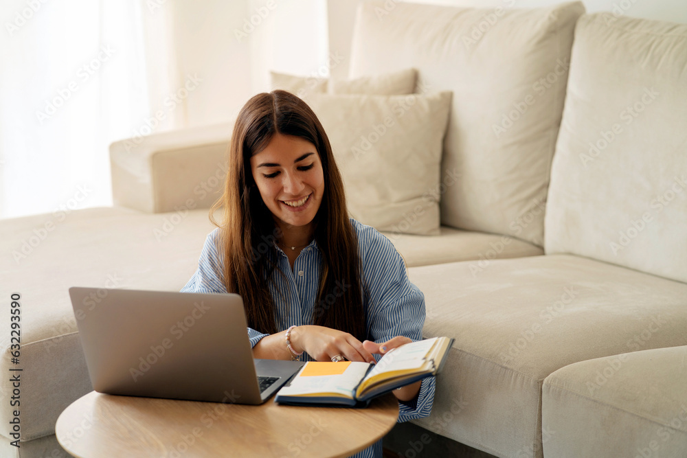 Smiling woman working on laptop in living room Smiling woman working on laptop in living room