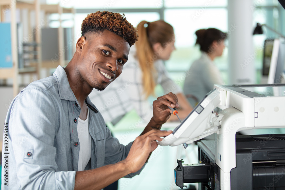 Fototapeta premium young man repair printer with two women on background