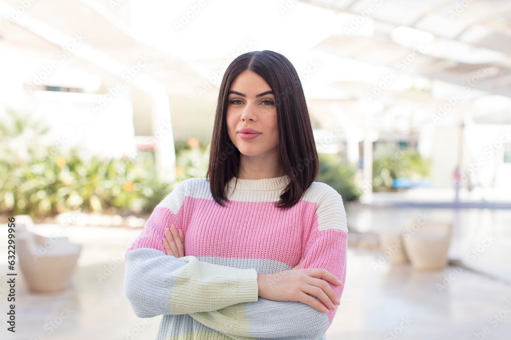 young pretty woman smiling to camera with crossed arms and a happy, confident, satisfied expression, lateral view young pretty woman smiling to camera with crossed arms and a happy, confident, satisfied expression, lateral view
