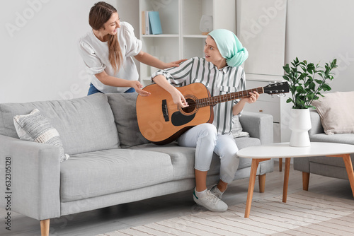 Teenage girl after chemotherapy playing guitar with her sister at home