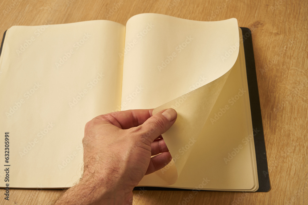 A white male hand turning the blank pages of a diary, notebook. A white male hand turning the blank pages of a diary, notebook.