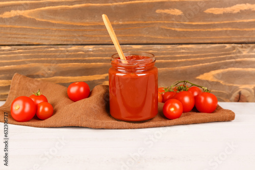 Jar with tasty tomato paste and fresh vegetables on table
