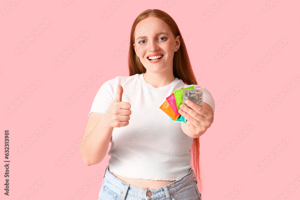 Young woman with condoms showing thumb-up on pink background Young woman with condoms showing thumb-up on pink background