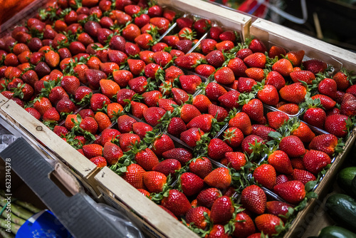 Fresh, beautiful, red, organic and delicious strawberries (Fragaria) at a local farmers market in a crate on shelves ready for customers.