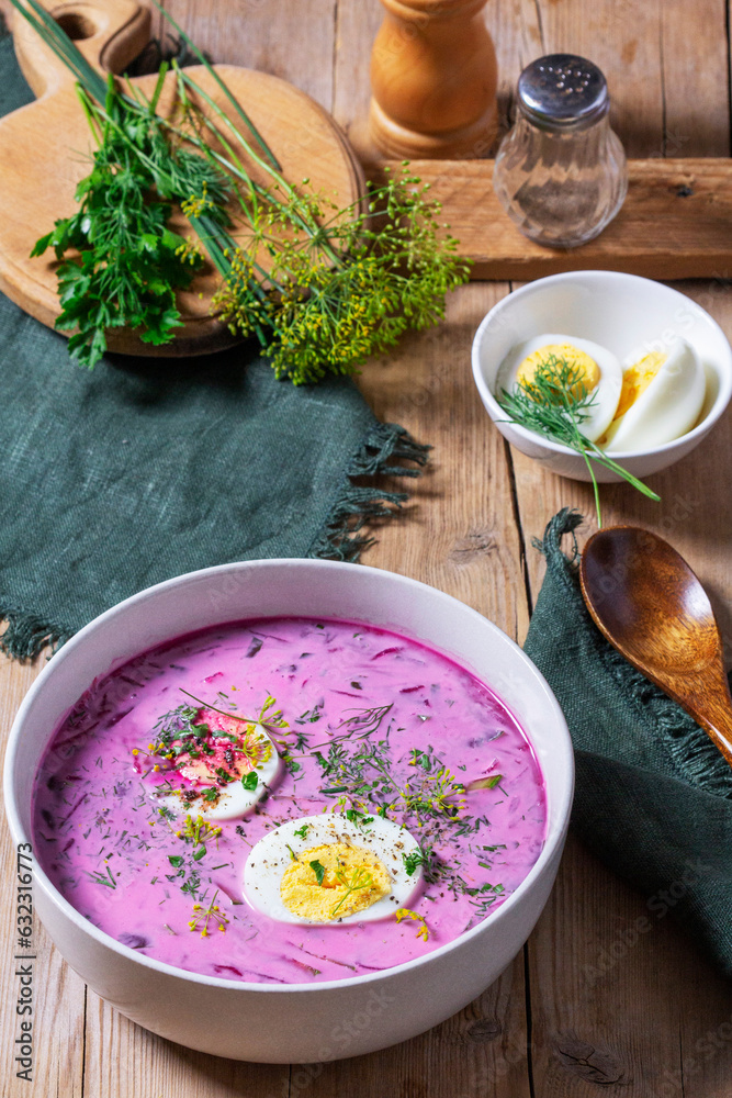 Traditional summer cold beetroot soup with cucumber, egg and sour cream on a wooden background. Rustic style.