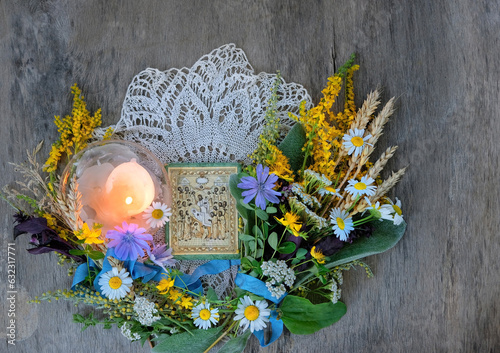 old orthodoxy icon, candle, herbs, flowers for sacred ritual on rustic wooden table. Herbal consecration - traditional popular customs on August 15th, day of the Assumption of Mary. Religious holiday