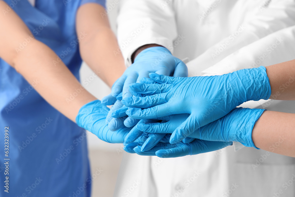 Doctors in medical gloves putting hands together at clinic, closeup Doctors in medical gloves putting hands together at clinic, closeup
