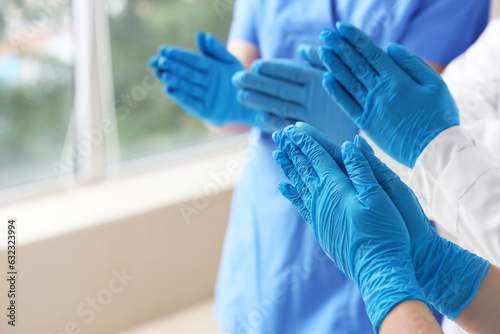 Doctors in medical gloves praying at clinic, closeup