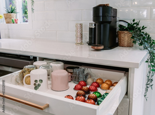 vue sur un comptoir de cuisine avec un tiroir ouvert nous montrant l'organisation des capsules à café et des tasses photo