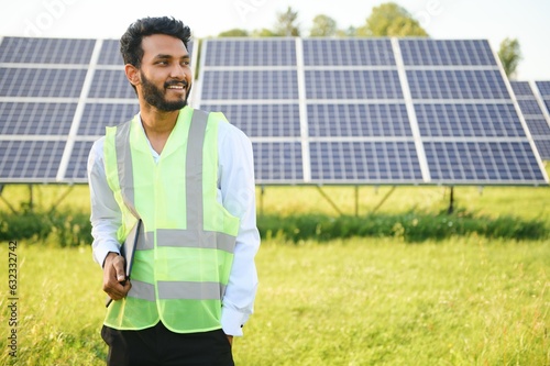 Portrait of Young indian male engineer standing near solar panels, with clear blue sky background, Renewable and clean energy. skill india, copy space. © Serhii