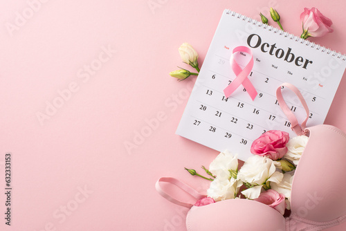 Early detection campaign setup. Top view of october calendar with pink ribbon, bra and eustoma flowers on pastel pink backdrop, providing space for informative text or advertisements