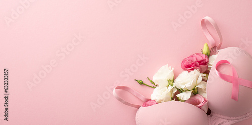 Breast cancer awareness theme: Overhead shot of a bra filled with delicate eustoma flowers, adorned with a pink ribbon symbol on a soft pink backdrop. Ample room for text or ads
