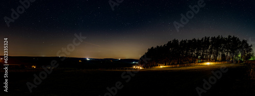 A panoramic view of the night sky over longnor wood in the English Peak District.