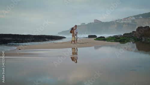 Sensual couple embracing beach with cloudy sky. Unknown man twirling woman dance