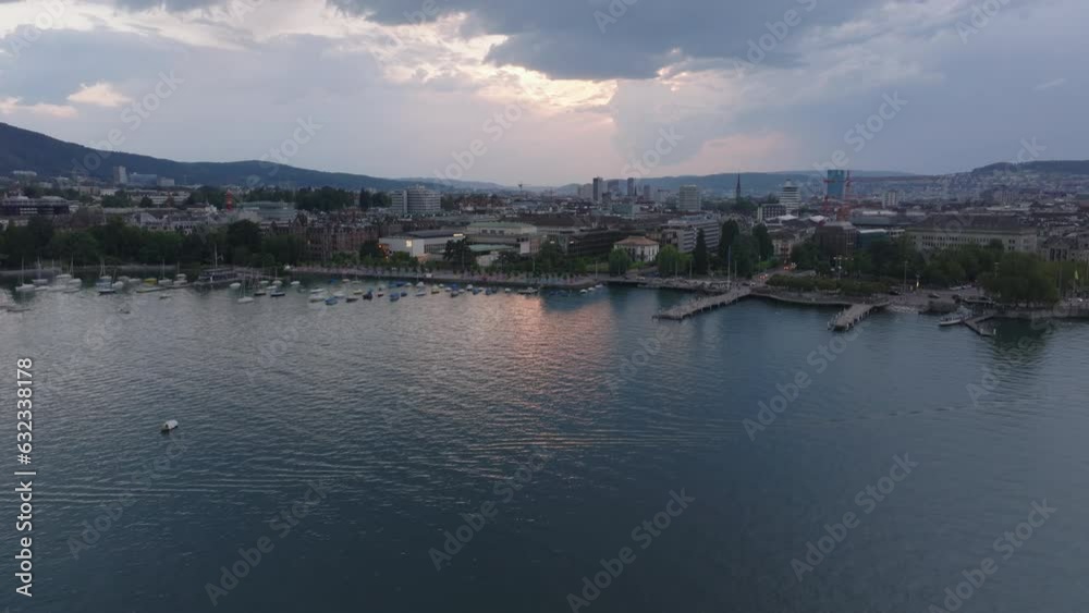 Aerial view of rippled lake surface and waterfront in city at cloudy sunset. Boats moored along bank. Zurich, Switzerland Aerial view of rippled lake surface and waterfront in city at cloudy sunset. Boats moored along bank. Zurich, Switzerland