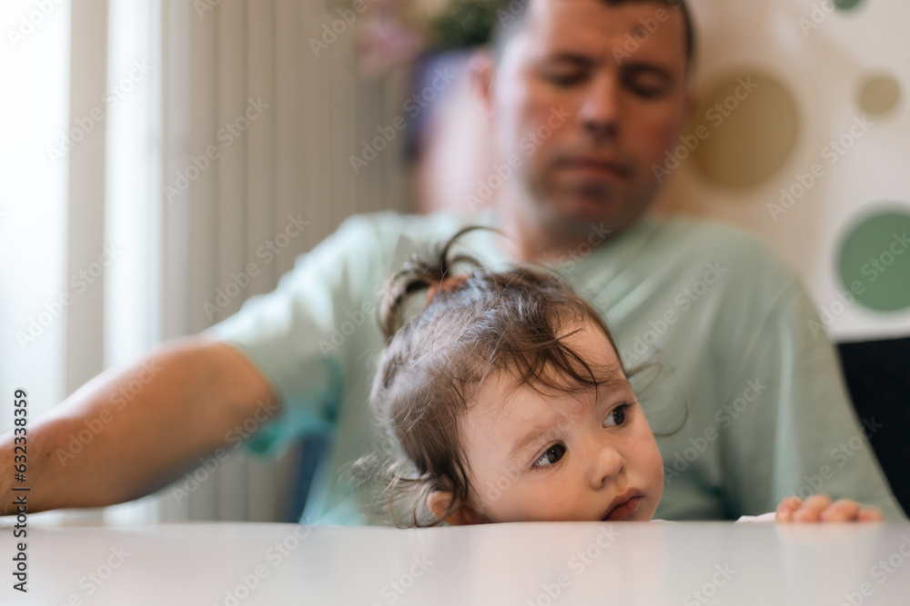 Portrait of a girl in her father's arms at the table. Portrait of a girl in her father's arms at the table.