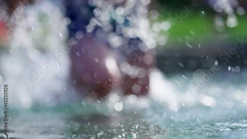 Joyful child running in swimming pool water splashing water in slow-motion during summer day. Active little boy sprinting at 120fps photo