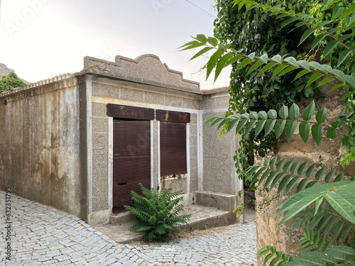 Frontal view of an abandoned old Greek grocery store in Tepekoy (Agridia) Gokceada, Turkey. shutters locked and rusted photo