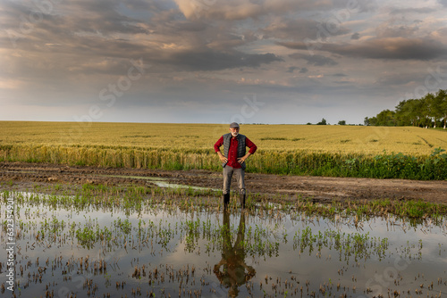 Disappointed farmer standing on flooded agricultural field