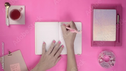 Flat lay top view of woman writing on pink background - Barbie Inspired photo