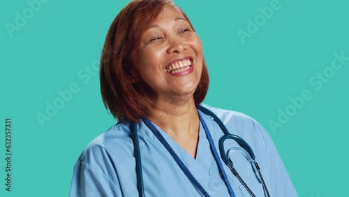 Upbeat chilled asian clinic worker having burst of laughter while at work. Close up of happy nurse enjoying amusing discussion with colleague during shift break, isolated over studio background