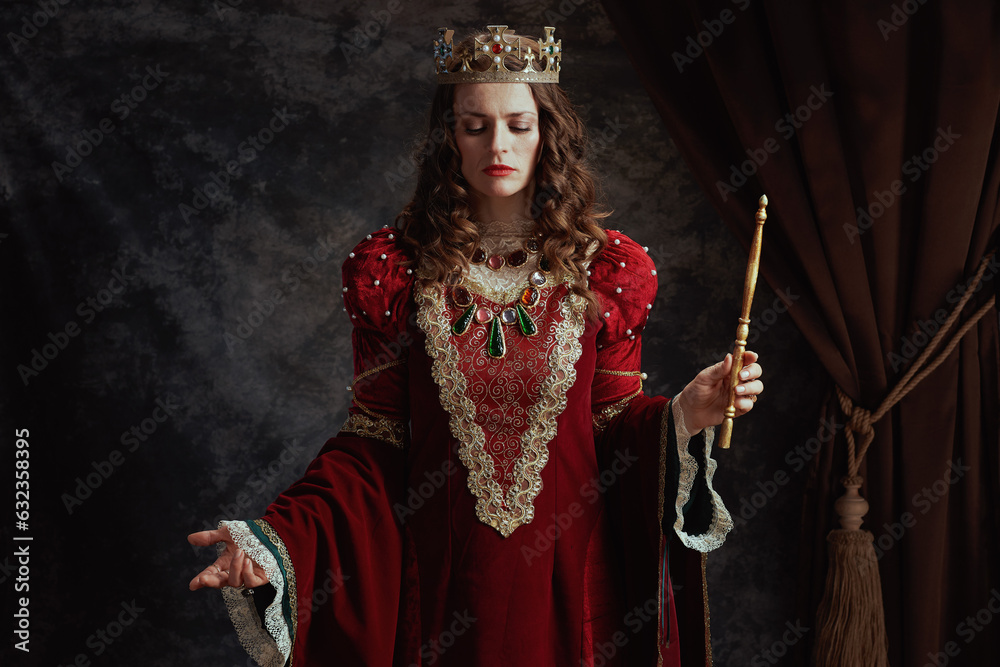 medieval queen in red dress with wand and crown