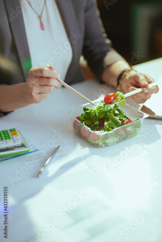 Modern woman employee in green office eating salad