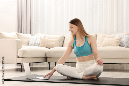 Woman in sportswear meditating near laptop at home