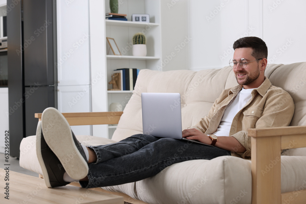 Happy man working with laptop on sofa at home Happy man working with laptop on sofa at home