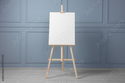 Wooden easel with blank canvas near grey wall indoors