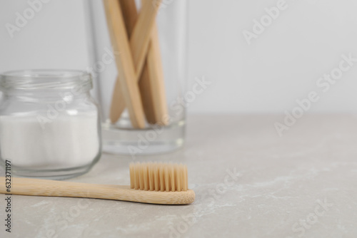 Foto Bamboo toothbrushes and jar of baking soda on light marble table, space for text