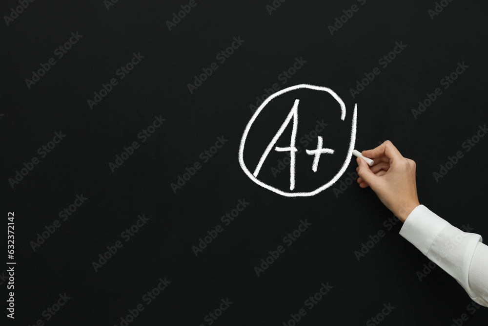 School grade. Teacher encircling letter A and plus symbol with chalk on blackboard School grade. Teacher encircling letter A and plus symbol with chalk on blackboard