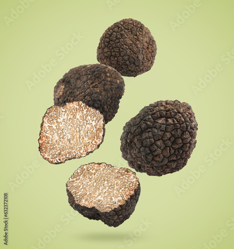 Cut and whole truffles falling on olive color background